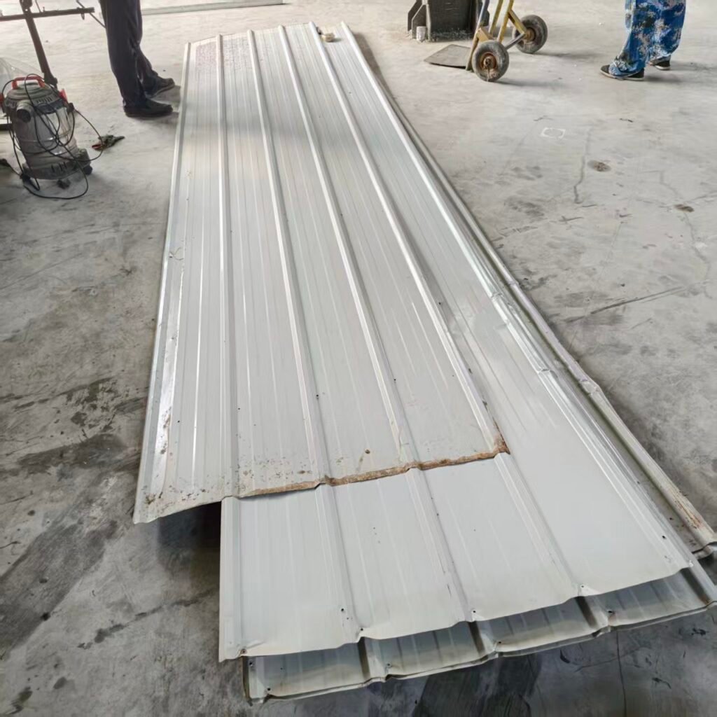 Reused profiled steel roofing sheets laid out on a factory floor before fitting