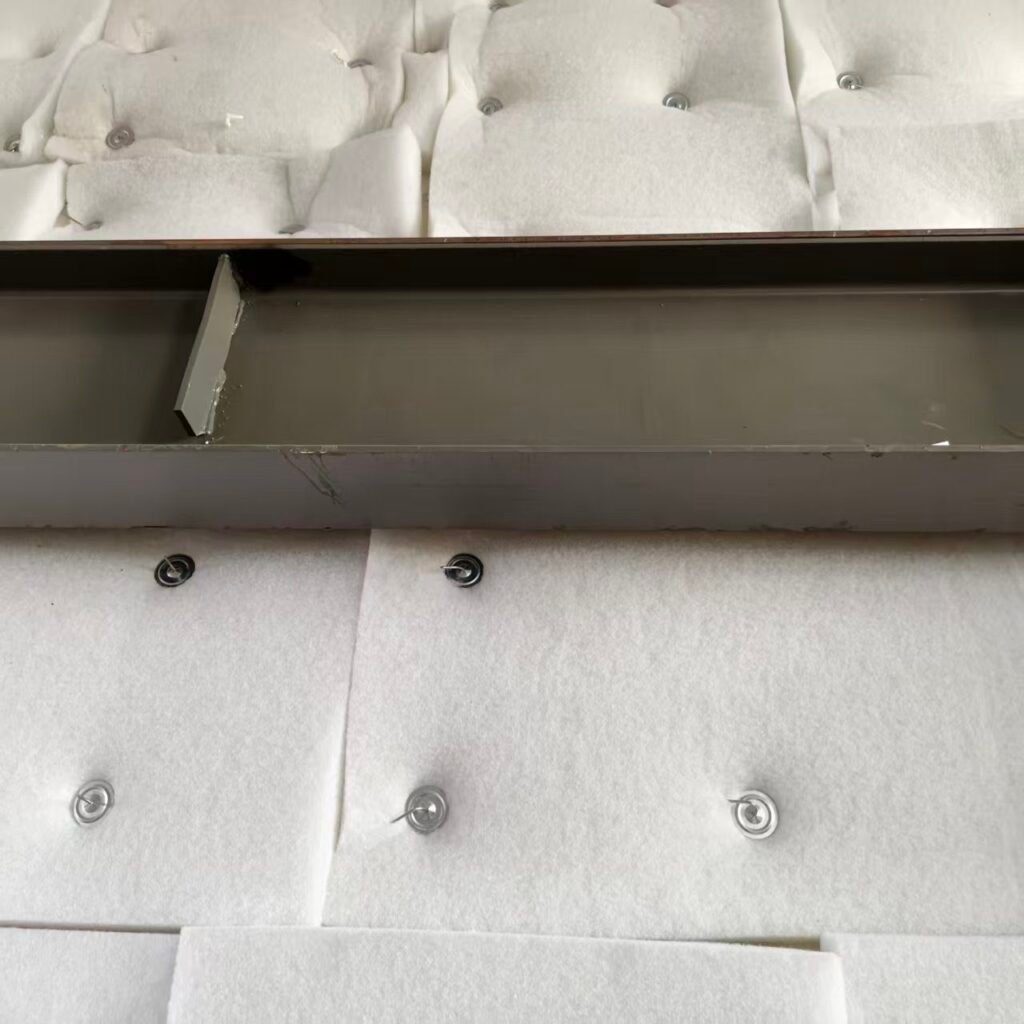 Self-locking washers pressed onto acoustic wool on a steel wall, surplus pins bent over